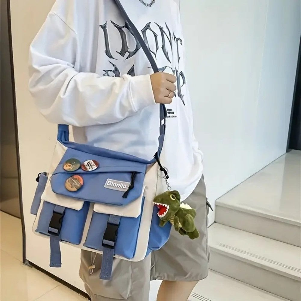 Person holding a blue backpack with various straps and a small plush toy, wearing a light-colored hoodie.